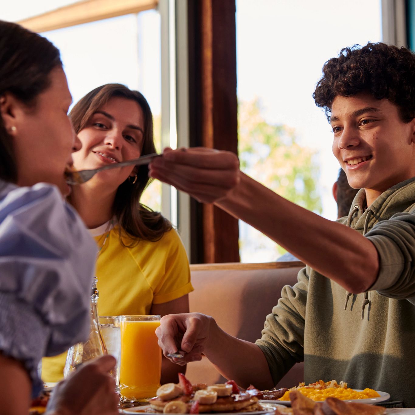 Niño alimentando a su madre en una mesa.