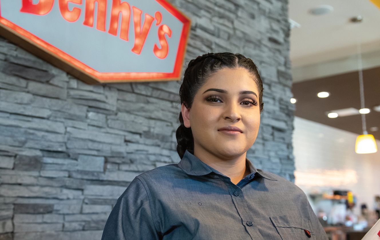 Mujer posa frente a un cartel de Denny's