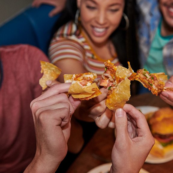 Group of people cheersing nachos