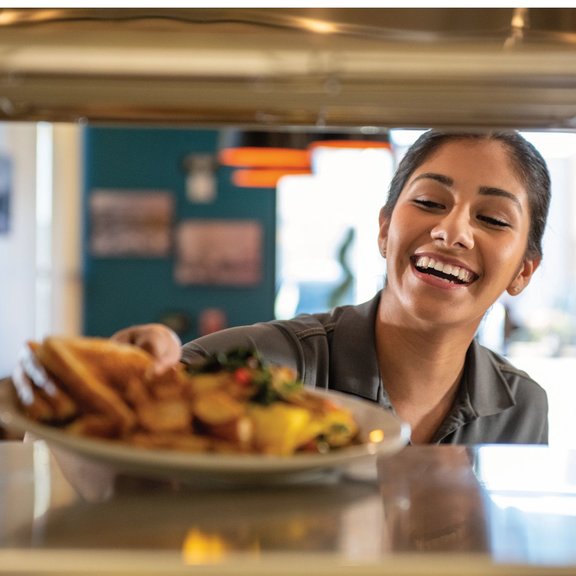 Female server picking up food from the kitchen