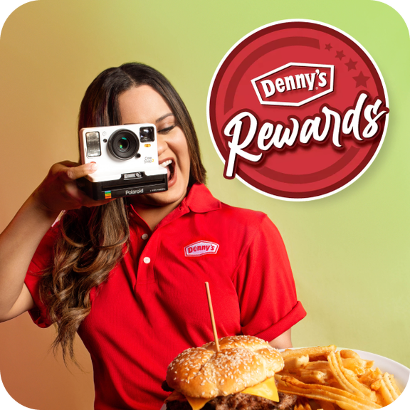 A woman in a Denny's uniform takes a photo of a Denny's meal with the Denny's Rewards logo in the background